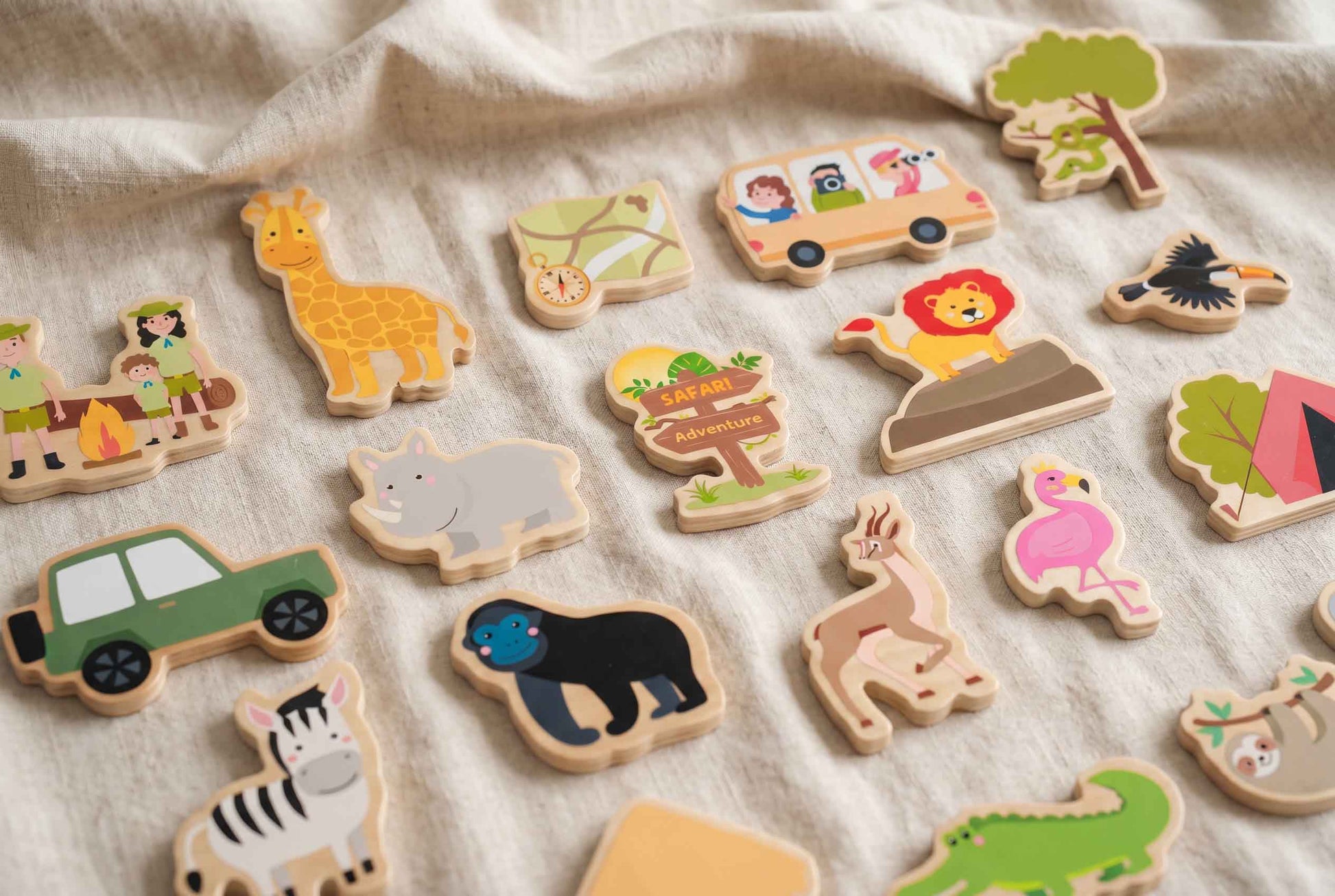 Holzspielzeug-Set zum Thema Safari mit verschiedenen Tieren, einem Safari-Bus und Campingszenen. Das Set enthält eine Giraffe, einen Löwen, ein Zebra und einen Flamingo. Die Spielzeuge sind in leuchtenden Farben bemalt.